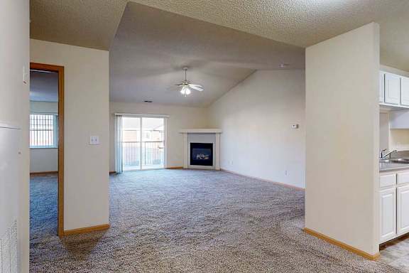 a spacious living room with a fireplace and a ceiling fan