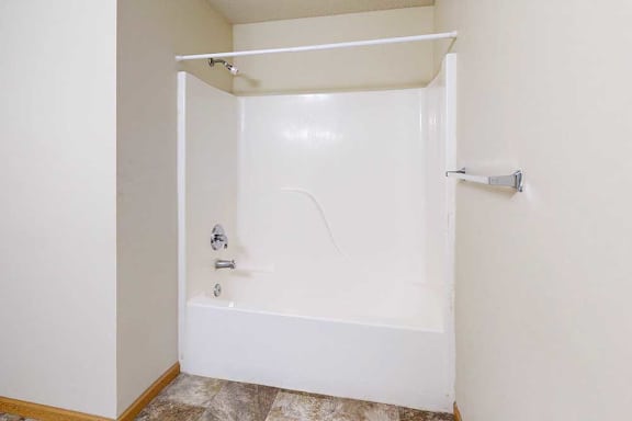 A white bathtub with a shower head and faucet.
