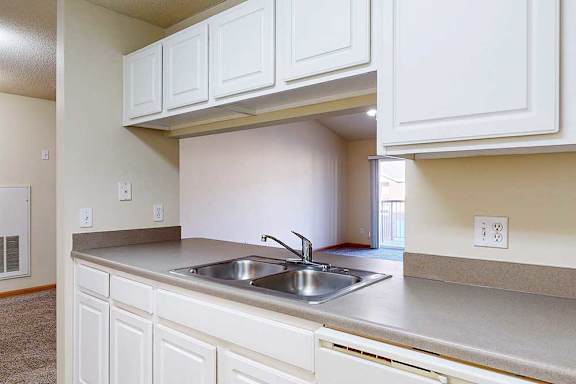 a kitchen with white cabinets and a stainless steel sink