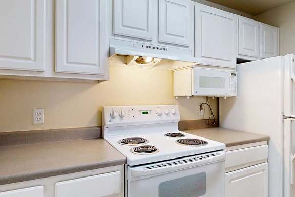 A white stove and oven in a kitchen with white cabinets.