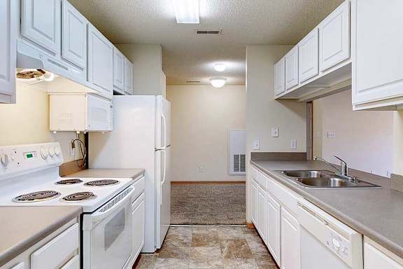 a galley-style kitchen with white appliances and cabinets