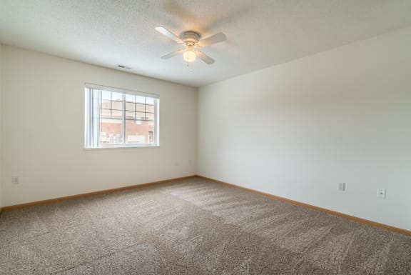 an empty room with a ceiling fan and a window