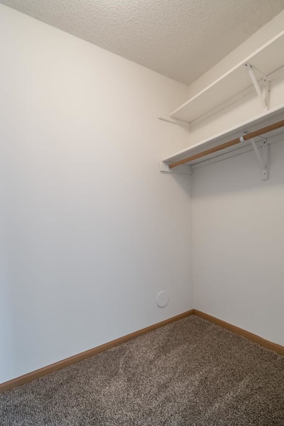 an empty room with a white wall and a shelf on the wall