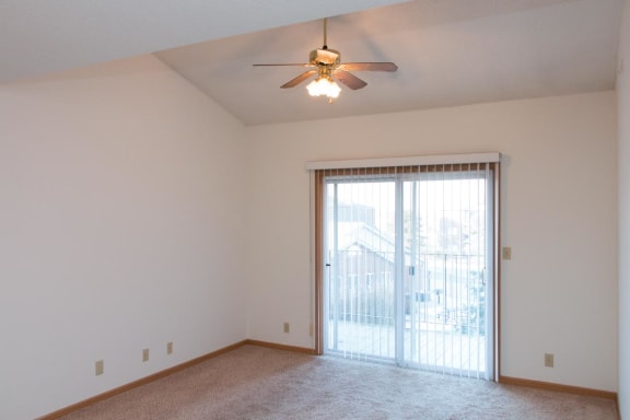 a living room with a ceiling fan and a door to a balcony