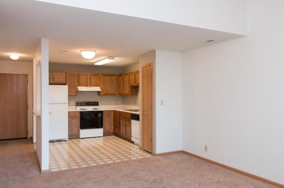 an empty kitchen with white appliances and wooden cabinets