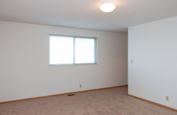 a large white room with a window and carpet