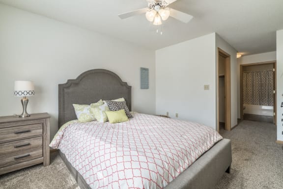 Master bedroom with ceiling fan and attached bathroom at Northridge Heights in Lincoln