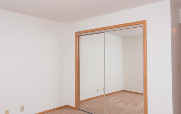 a bedroom with a mirrored closet door