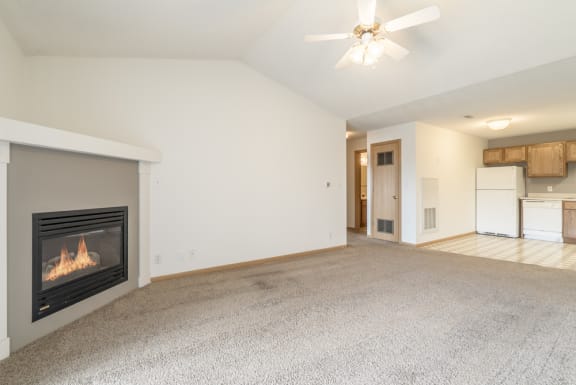 an empty living room with a fireplace and a kitchen