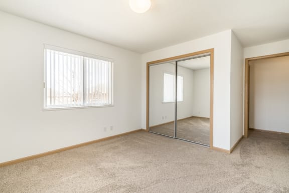 an empty bedroom with a mirrored closet door