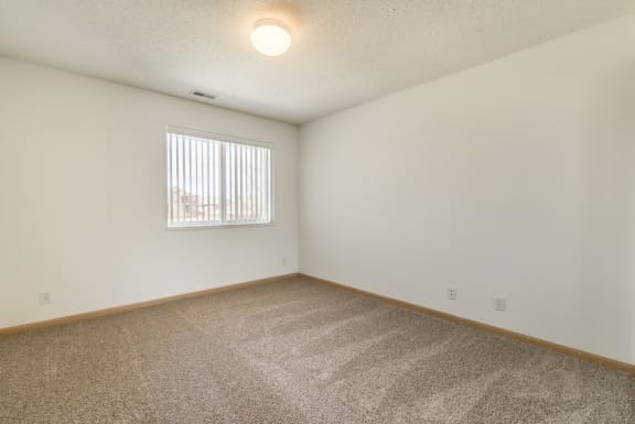 a spacious living room with carpet and a window