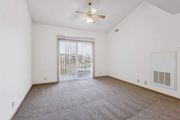 A room with a ceiling fan and a sliding glass door leading to a balcony.