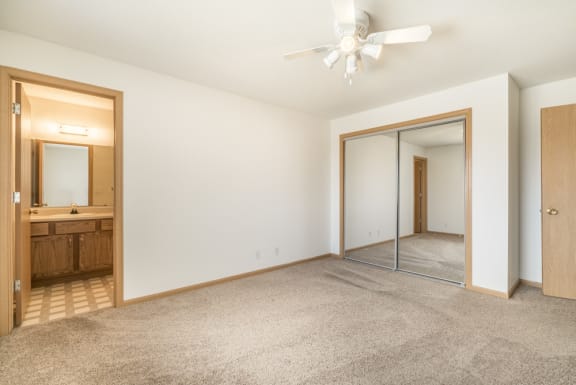 an empty living room with a mirror and a ceiling fan