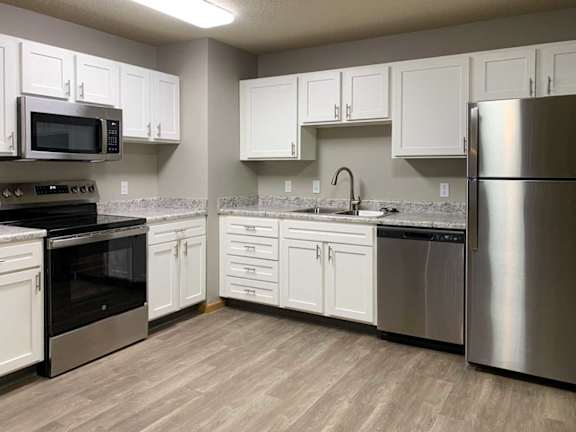 a kitchen with white cabinets, stainless appliances, and hardwood floors