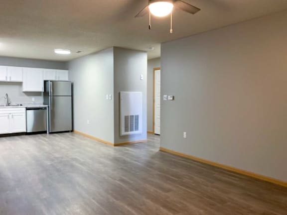 a kitchen with white cabinets and stainless steel appliances and a large living room with hardwood flooring