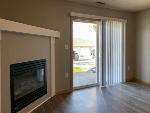 a living room with a fireplace and mantle next to a sliding glass door