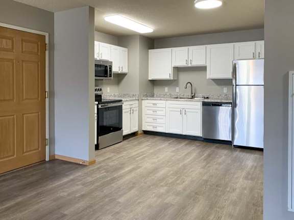 a kitchen with white cabinets and stainless steel appliances next to the front door