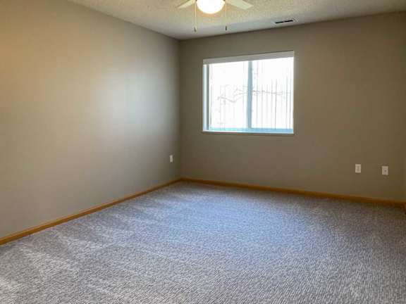 a bedroom with carpeted flooring, a large window, and a ceiling fan