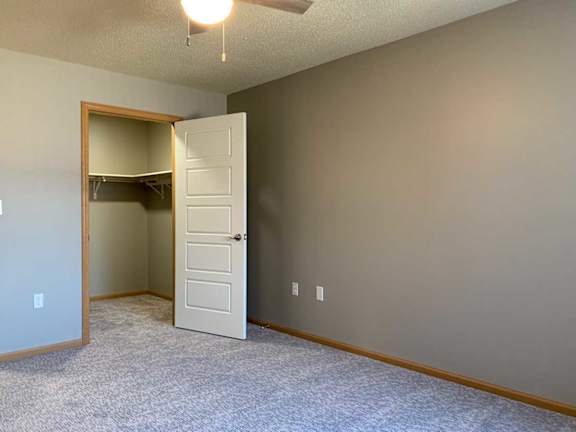 a bedroom with a door to a walk-in closet and a ceiling fan
