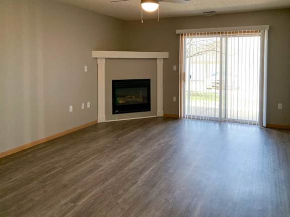 a spacious living room with a fireplace, a mantle, a sliding glass door to the patio, and a ceiling fan