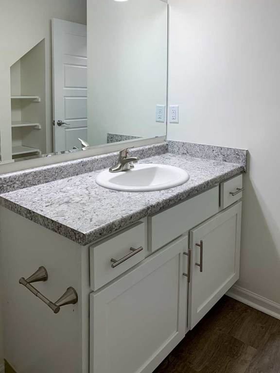a bathroom with a white vanity sink with granite countertops and overhead lighting