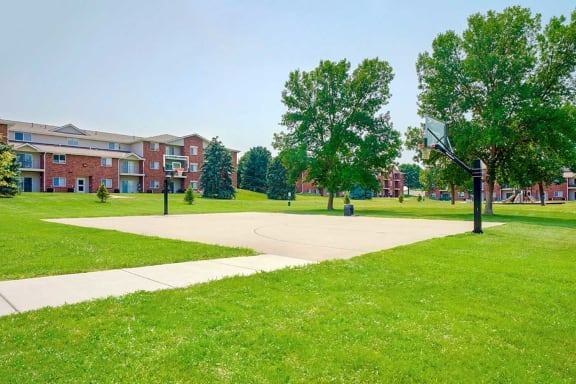Expansive green lawn with a basketball court and apartments in the background