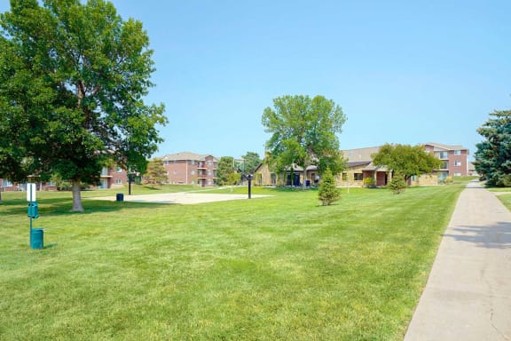 Expansive green lawn with walking paths and apartments in the background