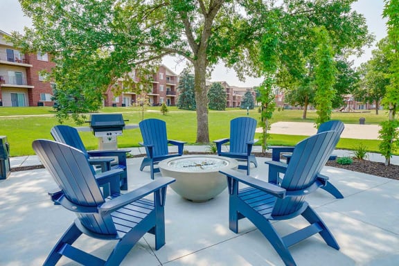 Outdoor seating area around a firepit with blue chairs