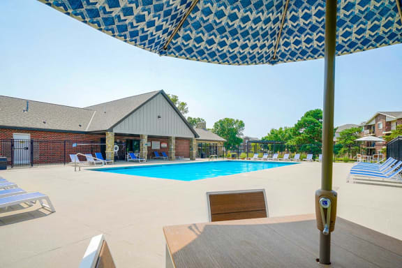 Swimming pool with an umbrella-covered table and chairs in the foreground