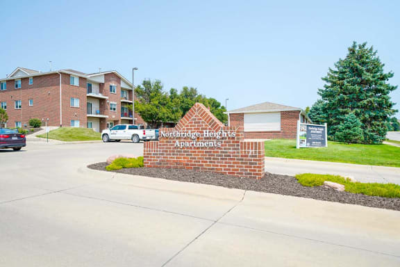 Brick monument entrance sign with landscaped greenery around it