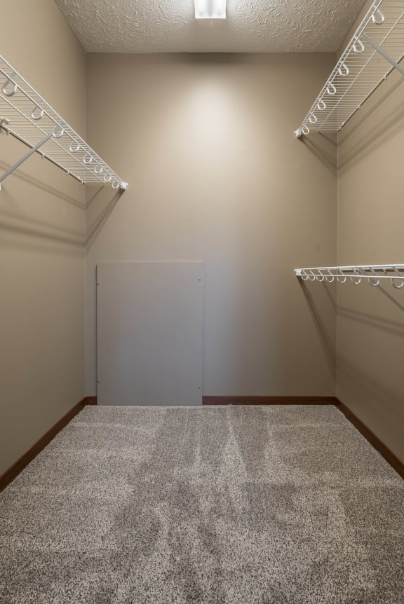 a large walk in closet with white shelves and a white door