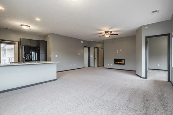 Living room with electric fireplace and ceiling fan at The Villas of Omaha at Butler Ridge in Omaha Nebraska