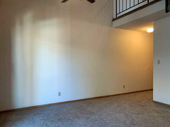 a living room with a vaulted ceiling, ceiling fan, and a loft area above