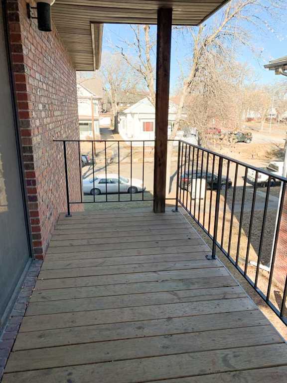 a wooden deck with a metal railing and a view of a street