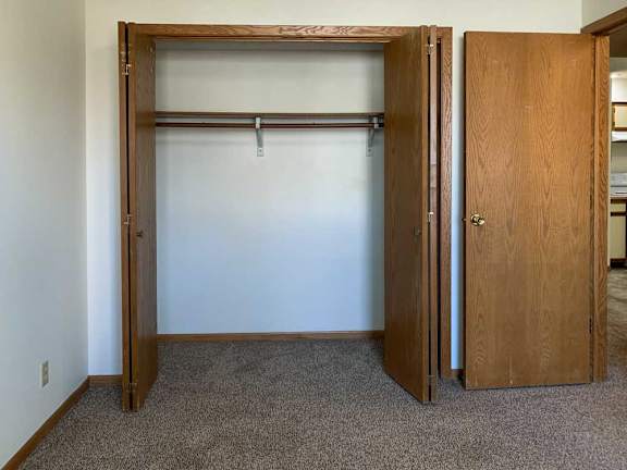 a bedroom closet with a white wall and a wooden door