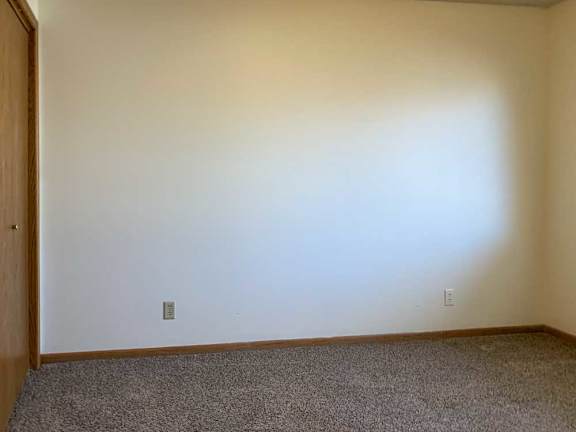 a bedroom with a carpeted floor and a door on the left