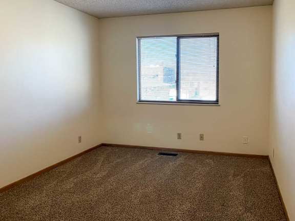 a bedroom with a window and carpeted floor