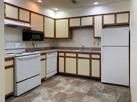 a kitchen with white appliances and white and wooden cabinets
