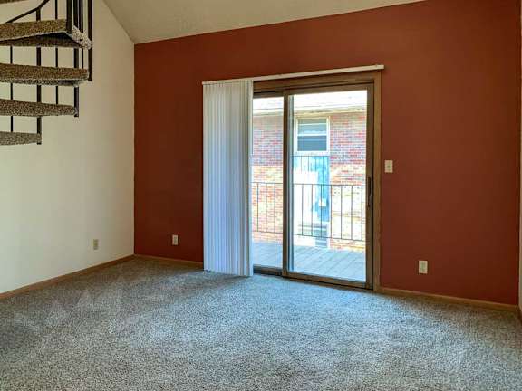 a living room featuring a rust-colored accent wall with a sliding glass door and vertical blinds