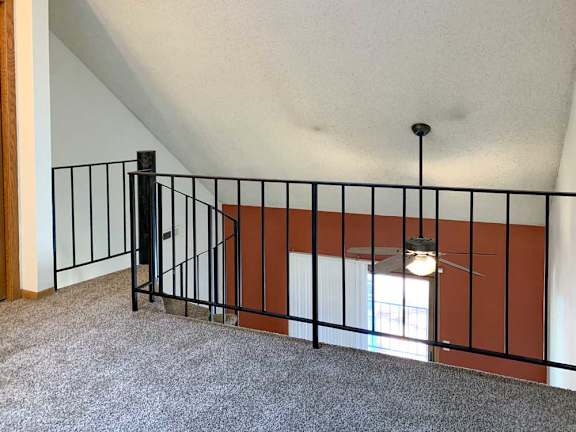a loft area with a carpeted floor and a view of the living room below