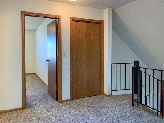 a loft area with a metal railing, a closet storage closet, and a door open to a bedroom