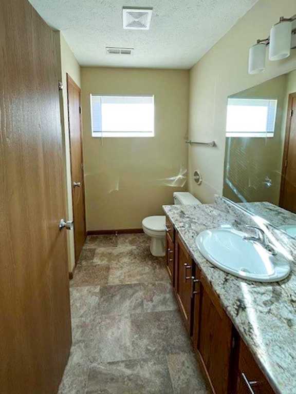 a bathroom with a vanity sink, a mirror, a linen closet, and a window