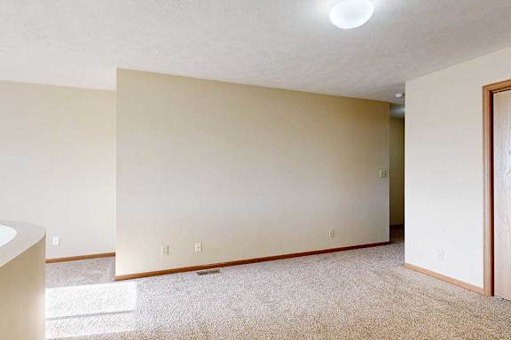 A carpeted loft bedroom with a view open to below and a sliding double-door closet.