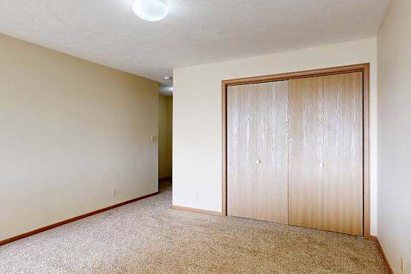 A carpeted loft bedroom with a sliding double-door closet.