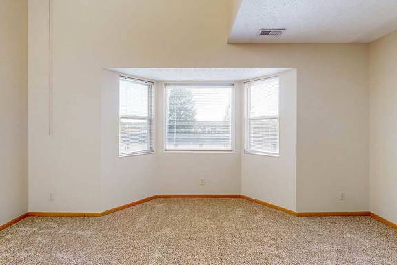 A carpeted living room with a bay window.