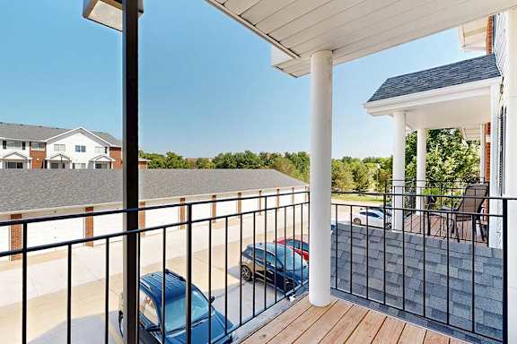 A balcony with a black metal railing and a view of neighboring apartments and greenery.