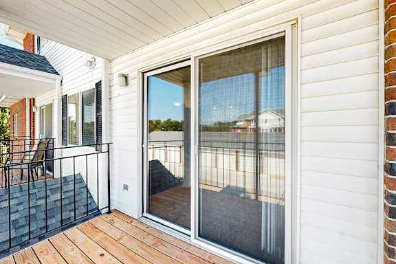 A balcony with a sliding glass door, and a metal railing.