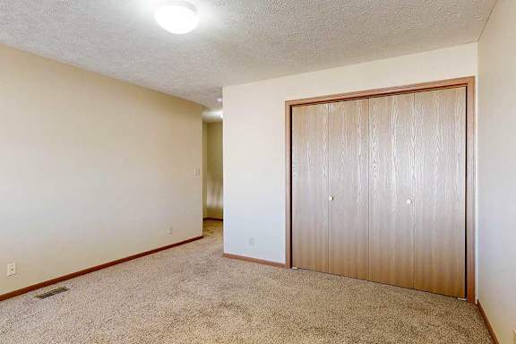 A loft bedroom with a carpeted floor and double-door closet.