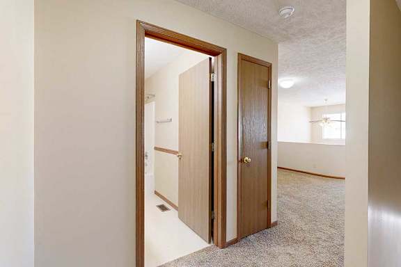 A hallway at the top of the stairs with a door to the loft bathroom and a linen closet.
