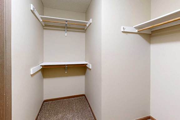A spacious walk-in closet with three built-in shelves and hanging space.